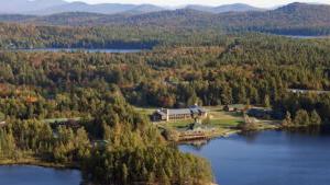 Aerial view of the Paul Smith's College campus with a lake in the foreground and mountains in the distance